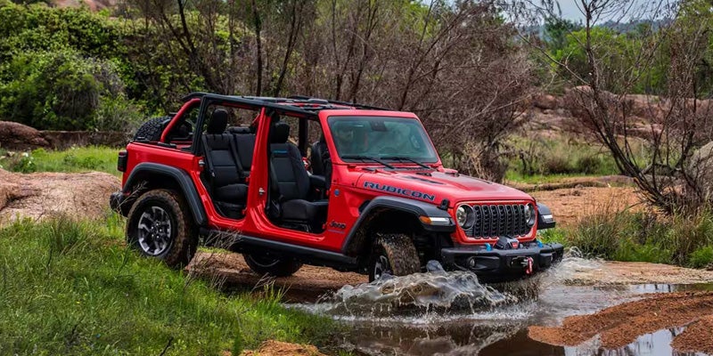 Red Jeep Wrangler driving through large puddle