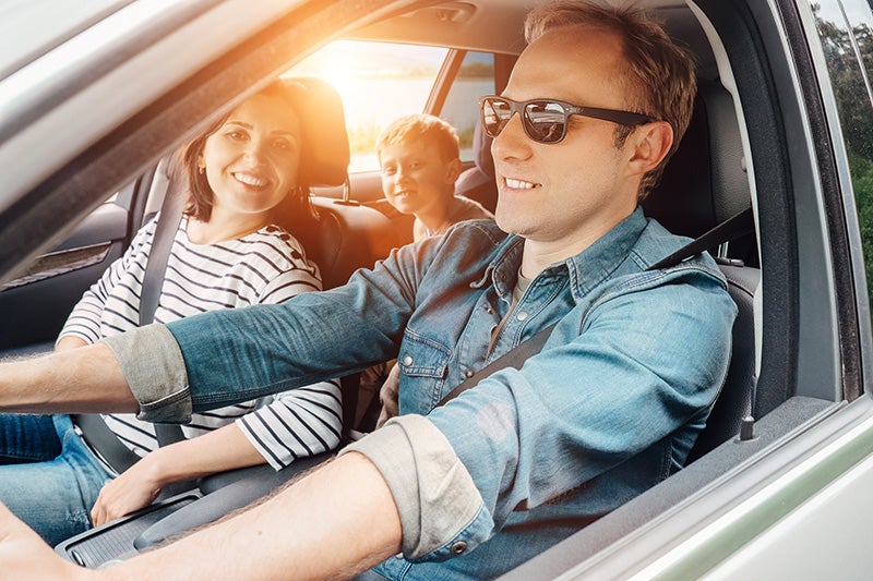 Family in car driving and smiling