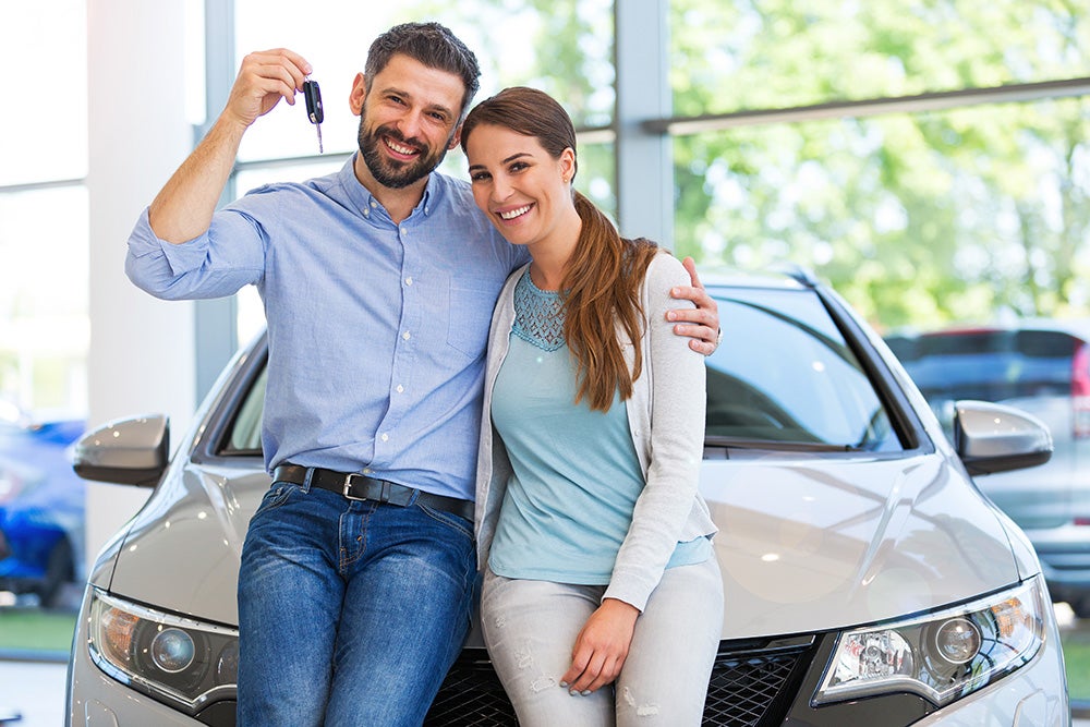 couple standing in front of car holding up new cary keys