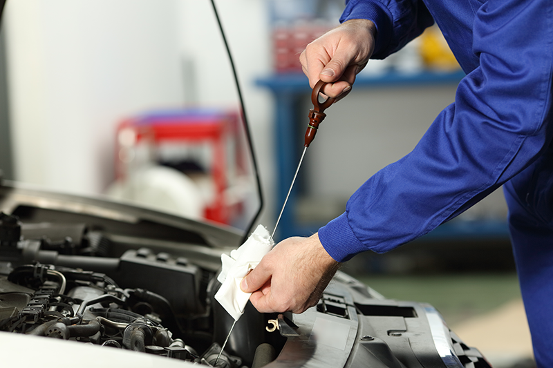 service technician checking dipstick for oil levels in car